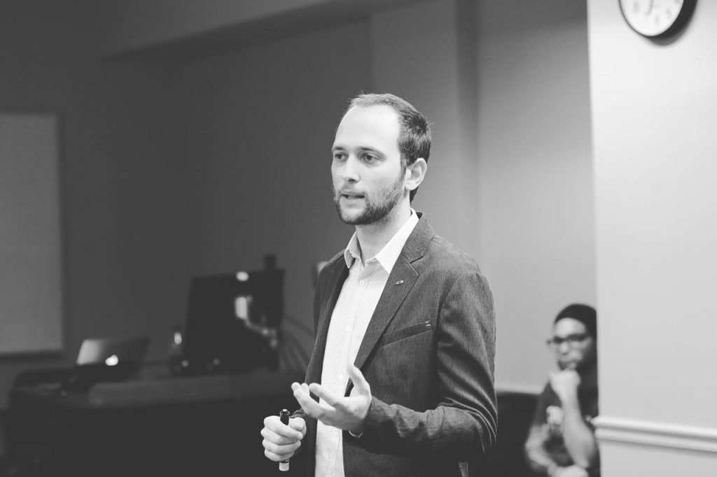 It's a black and white picture of Dr.  Raúl Carballo Rubio in a suit, left hand lifted in a speaking pose. 